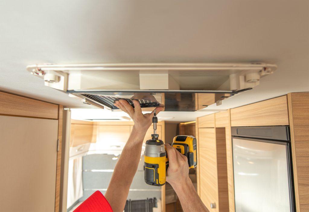 rv technician worker replacing air conditioner unit inside rv